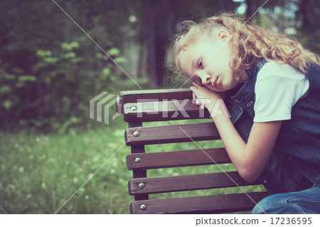 Portrait of sad blond little girl sitting on bench 17236595