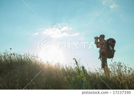 Young caucasian man with backpack standing on the top of hill 17237390