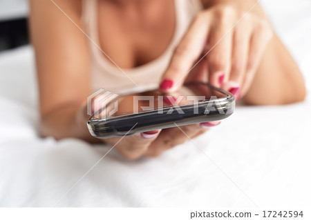 young woman using a smartphone in bed young woman using a smartphone in bed 17242594