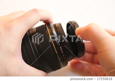 Hand moving lens cap on a white background Hand moving lens cap on a white background 17250018