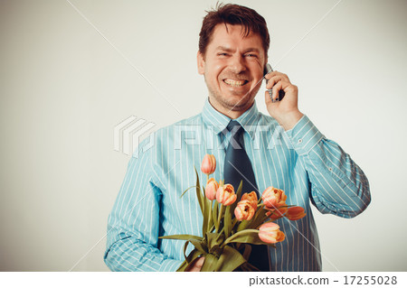Businessman smiling while phoning, holding tulips Businessman smiling while phoning, holding tulips 17255028
