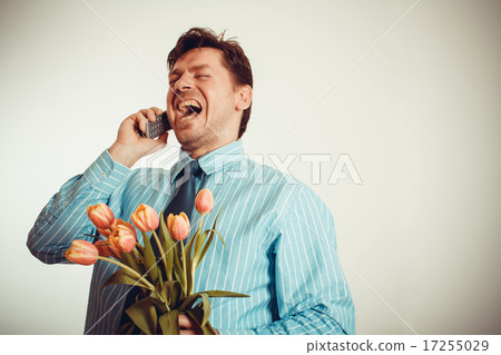 Businessman smiling while phoning, holding tulips Businessman smiling while phoning, holding tulips 17255029