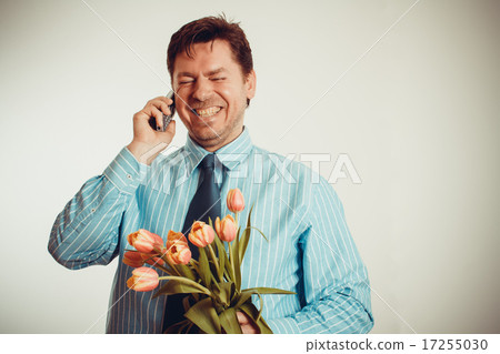 Businessman smiling while phoning, holding tulips Businessman smiling while phoning, holding tulips 17255030