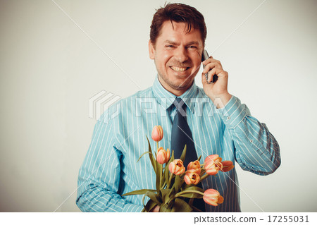 Businessman smiling while phoning, holding tulips 17255031