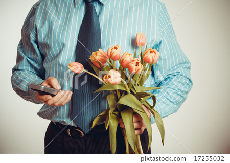 Businessman smiling while phoning, holding tulips Businessman smiling while phoning, holding tulips 17255032