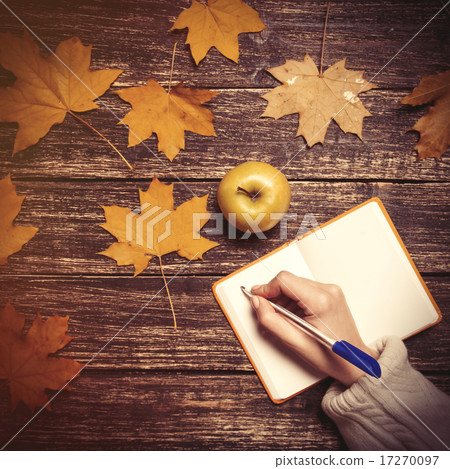 Female hand writing something in notebook next to apple 17270097