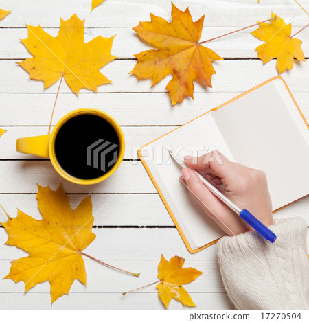 Female hand writing something in notebook near cup of coffee. 17270504