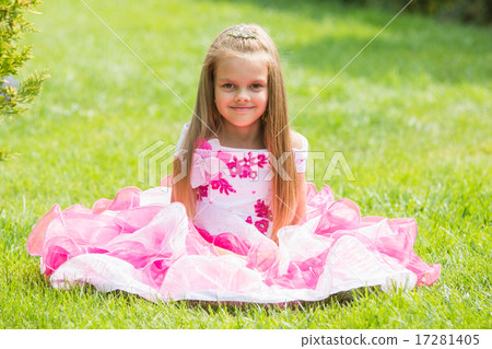 Five-year girl in a beautiful dress sat on the lawn in the green garden 17281405