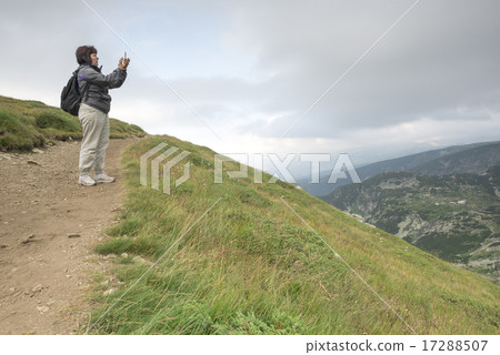 Senior woman taking photos with smartphone on the mountain Senior woman taking photos with smartphone on the mountain 17288507