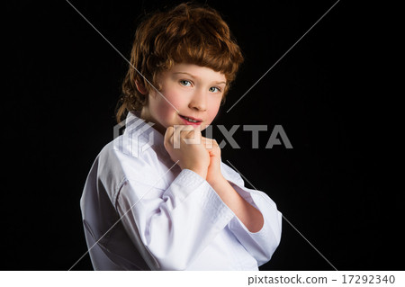 Smiling karate boy in white kimono isolated on black background 17292340