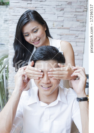 A woman surprising her boyfriend at a cafe. 17296537