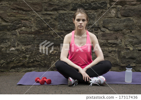 Sporty woman sitting resting on a yoga mat. Sporty woman sitting resting on a yoga mat. 17317436
