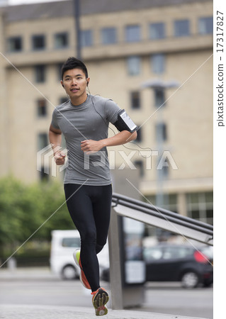 Asian running man, listening to music on smart phone while runni Asian running man, listening to music on smart phone while runni 17317827