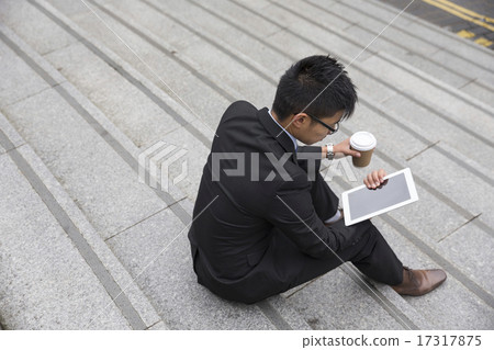 Overhead view of Asian businessman sitting on steps using a tab 17317875