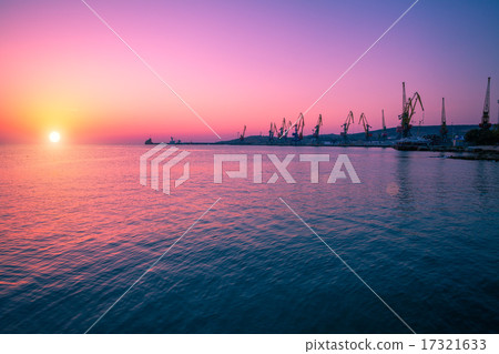 Sunrise over stone beach with port 17321633