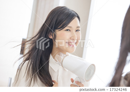 一個女人用吹風機烘乾她的頭髮 17324246