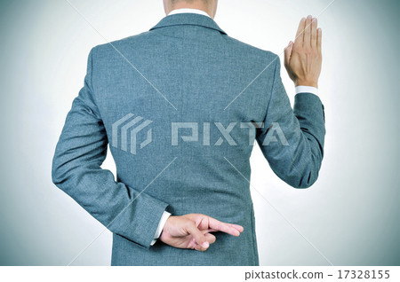 man swearing an oath, crossing his fingers in back man swearing an oath, crossing his fingers in back 17328155