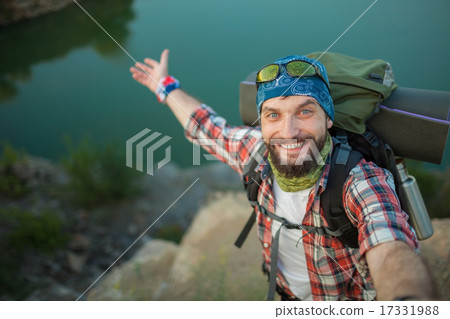 Young caucasian man with backpack standing on the top of hill Young caucasian man with backpack standing on the top of hill 17331988