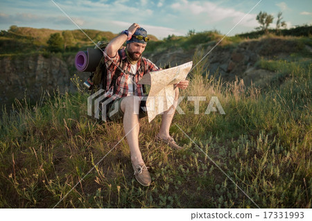 Young caucasian man with backpack sitting on the top of hill Young caucasian man with backpack sitting on the top of hill 17331993