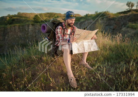 Young caucasian man with backpack sitting on the top of hill Young caucasian man with backpack sitting on the top of hill 17331994