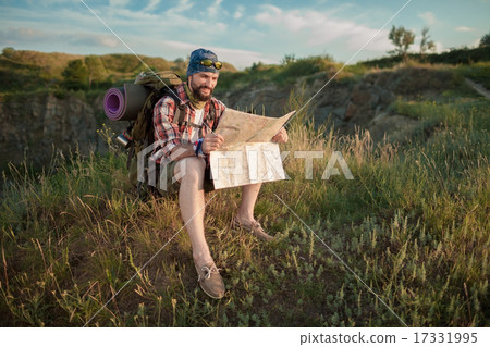 Young caucasian man with backpack sitting on the top of hill Young caucasian man with backpack sitting on the top of hill 17331995