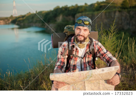 Young caucasian man with backpack sitting on the top of hill Young caucasian man with backpack sitting on the top of hill 17332023