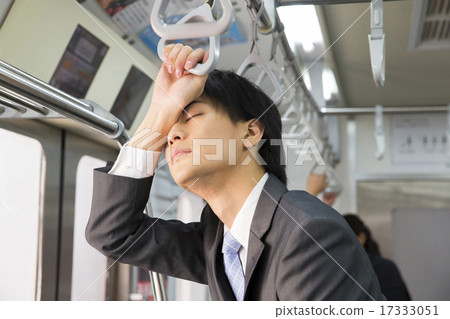 A businessman sleeping while standing in the train 17333051