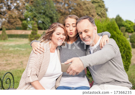 Pretty mature family is photographing themselves in park Pretty mature family is photographing themselves in park 17366235