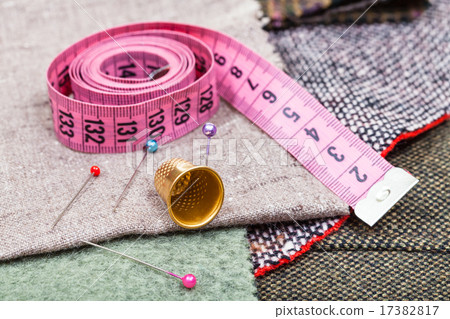 pink measure tape, pins, thimble on textile 17382817