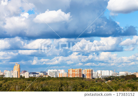 low blue clouds over green forest and city 17383152