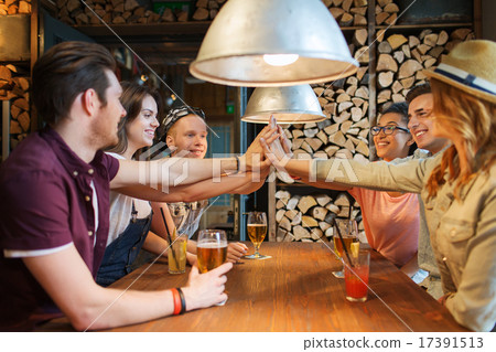 happy friends with drinks making high five at bar 17391513