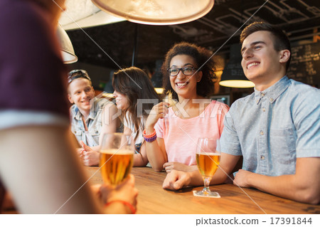 happy friends drinking beer and talking at bar 17391844
