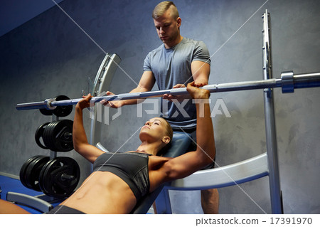 man and woman with barbell flexing muscles in gym man and woman with barbell flexing muscles in gym 17391970