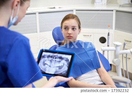 dentist showing x-ray on tablet pc to patient girl 17392232
