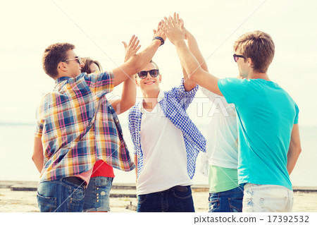 group of smiling friends making high five outdoors 17392532