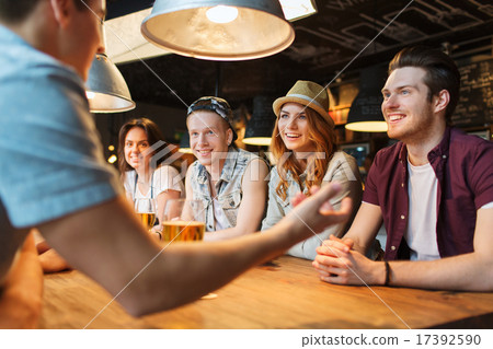happy friends drinking beer and talking at bar 17392590