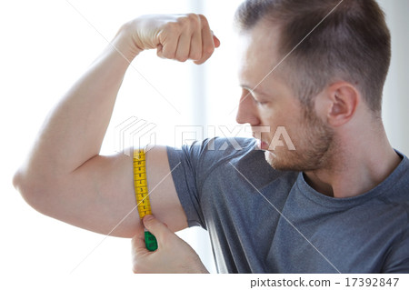 close up of male hands with tape measuring bicep close up of male hands with tape measuring bicep 17392847