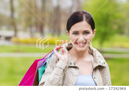 smiling woman with shopping bags coming from sale 17392969