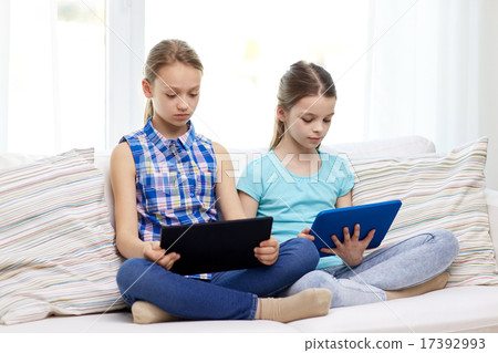 girls with tablet pc sitting on sofa at home girls with tablet pc sitting on sofa at home 17392993