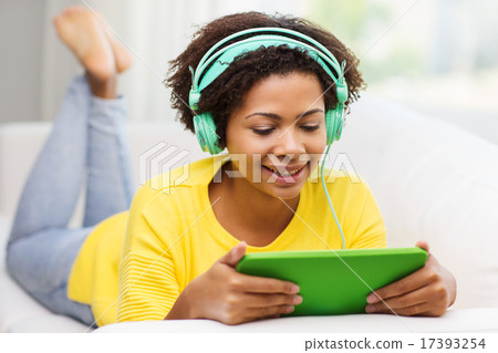 happy african woman with tablet pc and headphones 17393254