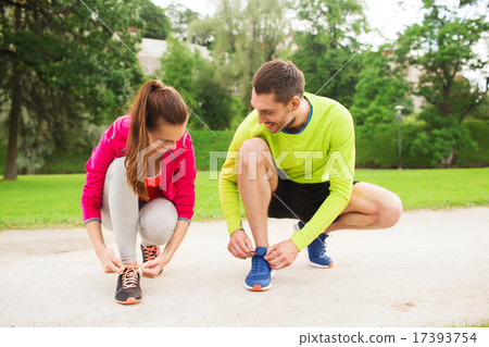 smiling couple tying shoelaces outdoors 17393754
