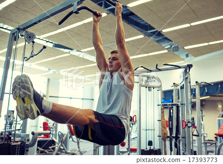 man flexing abdominal muscles on pull-up bar 17393773