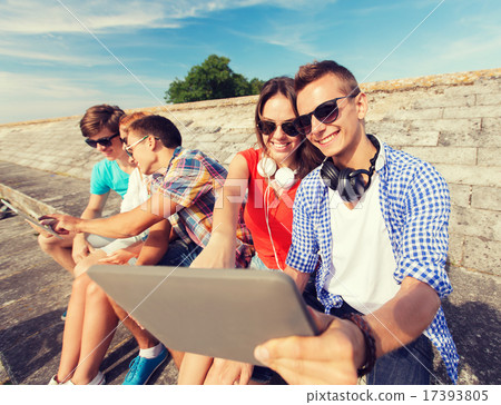 group of smiling friends with tablet pc outdoors 17393805