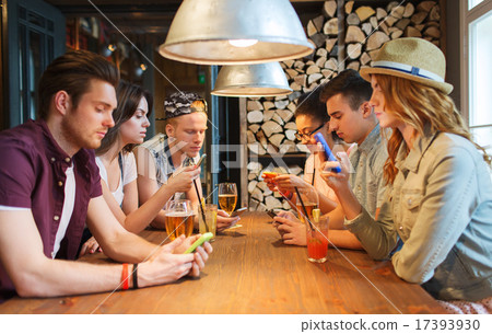 friends with smartphones and drinks at bar 17393930
