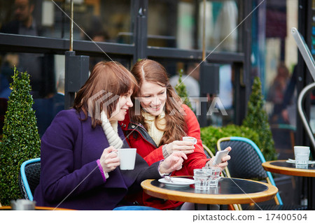 Two cheerful girls taking selfie in a Parisian cafe 17400504
