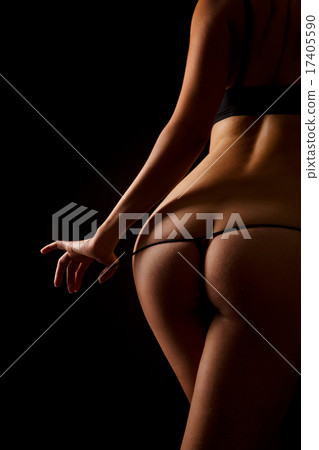 Woman pulling off her underwear over black background. 17405590