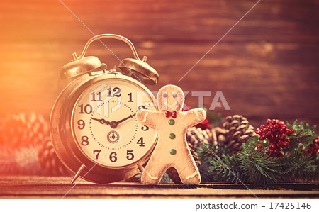 Alarm clock near Pine branches and gingerbread on wooden table. Alarm clock near Pine branches and gingerbread on wooden table. 17425146
