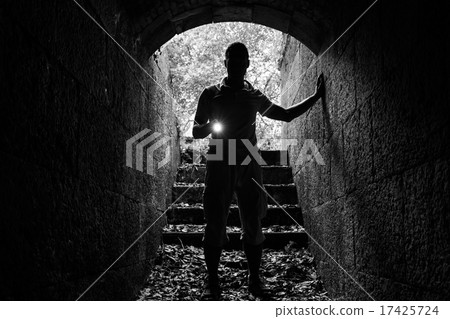 Young man with a flashlight in stone tunnel 17425724