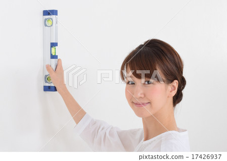 A woman confirming the distortion of a wall with a level 17426937