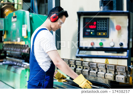 Asian machine operator in production plant 17438257